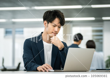 Businessman in his thirties thinking while looking at the laptop screen 105069381