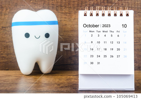 The October 2023 Monthly desk calendar for 2023 year with Model tooth on wooden table. The October 2023 Monthly desk calendar for 2023 year with Model tooth on wooden table. 105069413