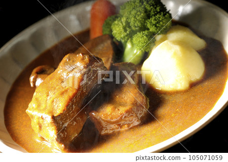 Hot beef stew with thickly sliced beef tongue, garnished with broccoli, carrots and potatoes 105071059