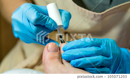 Pedicure. Master applies colorless base Pedicure. Master applies colorless base 105071203