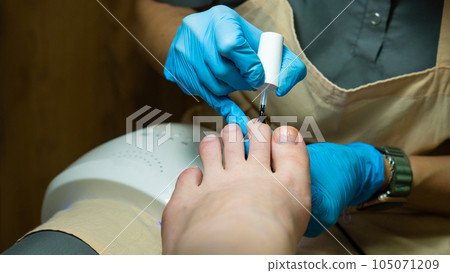 Pedicure. Master applies colorless base 105071209