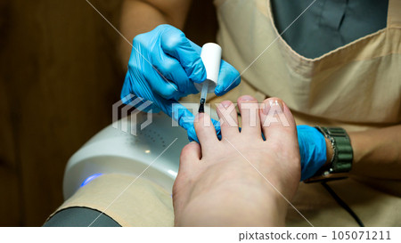 Pedicure. Master applies colorless base 105071211