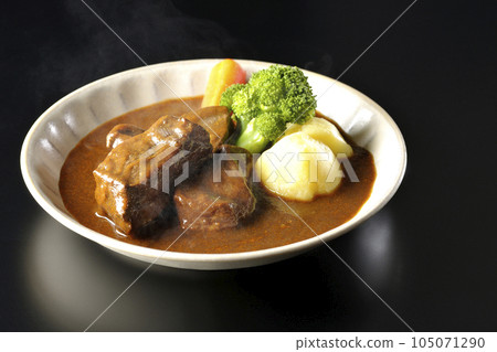 Hot beef stew with broccoli, carrots and potatoes, shot against a black background Hot beef stew with broccoli, carrots and potatoes, shot against a black background 105071290