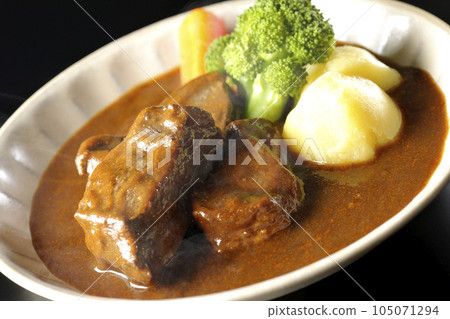 Hot beef stew with broccoli, carrots and potatoes, shot against a black background 105071294