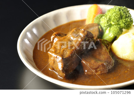 Hot beef stew with broccoli, carrots and potatoes, shot against a black background Hot beef stew with broccoli, carrots and potatoes, shot against a black background 105071296