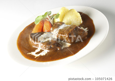 Hot beef stew with watercress, carrot, potato garnish and thick-sliced beef tongue covered with fresh cream, photographed against a white background 105071426