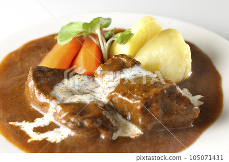 Hot beef stew with watercress, carrot, potato garnish and thick-sliced beef tongue covered with fresh cream, photographed against a white background 105071431