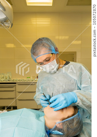 Dental surgeon examines patient's mouth Dental surgeon examines patient's mouth 105072870