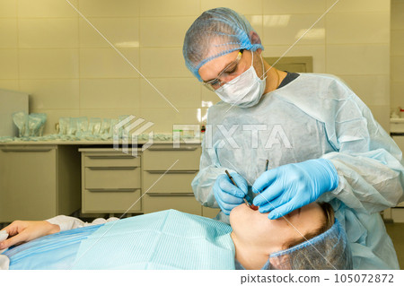 Dental surgeon examines patient's mouth Dental surgeon examines patient's mouth 105072872