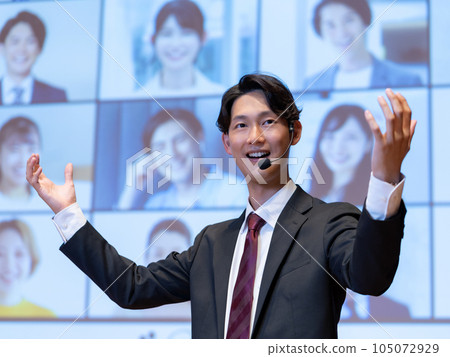 一位男講師在大廳里為通過可視電話與觀眾連接的人進行講座 105072929