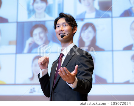 A male lecturer giving a lecture to a person who is connected to the audience by videophone in the hall A male lecturer giving a lecture to a person who is connected to the audience by videophone in the hall 105072934