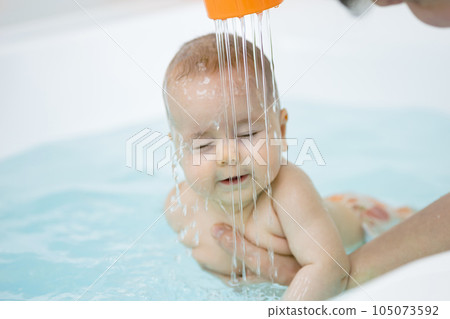 Baby girl splashes hands and kicks legs swimming forward 105073592