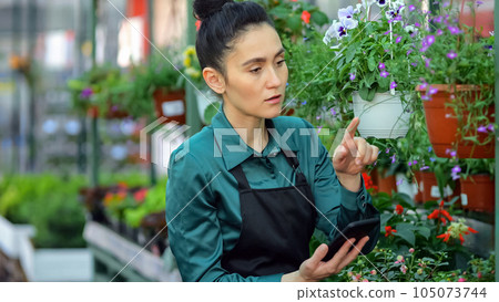 Lady florist enters information on flowers quantity in tablet Lady florist enters information on flowers quantity in tablet 105073744