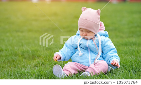 Toddler enjoys sitting on grass and playing with dandelion 105073764
