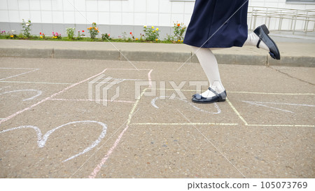 Junior school girl plays hopscotch in empty schoolyard 105073769
