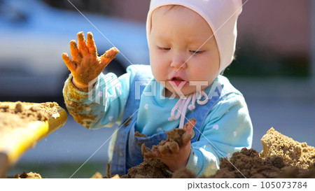 Toddler girl enjoys playing with sand on playground Toddler girl enjoys playing with sand on playground 105073784