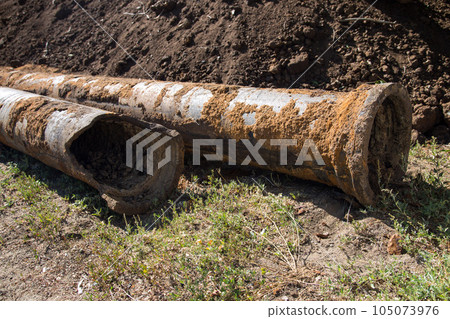 Replacement of the city water supply, old rusty pipes among the heaps of earth 105073976