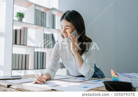 Beautiful young teen asian businesswoman using computer and smartphone mobile with planning working on financial document, tax, exchange, accounting and Financial advisor. 105074378