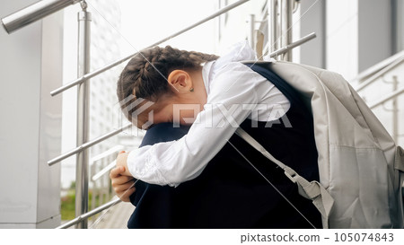 Schoolgirl sitting on stairs cries because of bullying 105074843