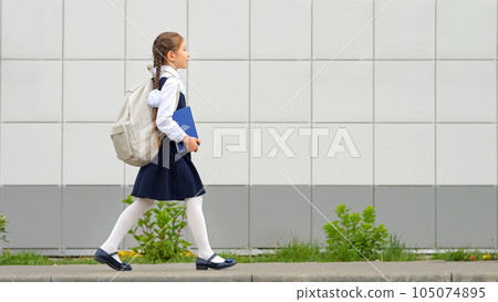 Schoolgirl carrying backpack and book goes to school Schoolgirl carrying backpack and book goes to school 105074895