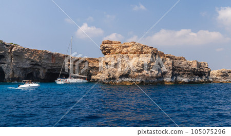 Motor boats with tourists sails coastal caves at Blue Lagoon of Comino 105075296