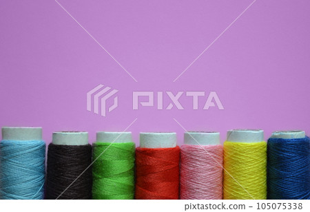spools of thread on a pink background, tailoring, photos for a sewing workshop, a banner for an atelier, sewing threads, a place for text 105075338