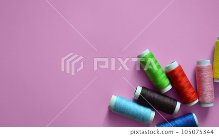 spools of thread on a pink background, a banner for an atelier, tailoring, sewing threads, a photo for a sewing workshop, a place for text 105075344