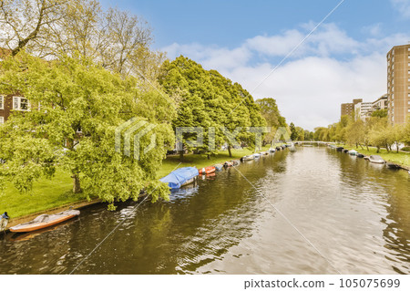 some boats in the water with buildings on either sides and trees growing along the riverbank, as seen from above 105075699