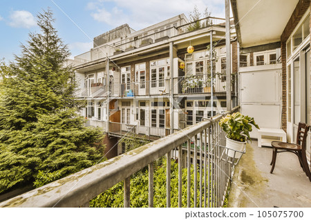 a balcony with some trees and buildings in the background, taken from an apartment window looking out onto the street 105075700