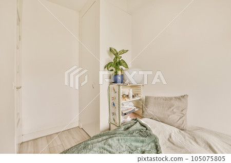 a bedroom with white walls and light wood flooring the room has a small bed, a plant on top shelf next to it a bedroom with white walls and light wood flooring the room has a small bed, a plant on top shelf next to it 105075805