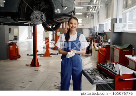 Portrait of beautiful smiling woman mechanic wiping hands with rag 105076776