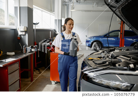 Young woman preparing fresh engine oil for replacement 105076779
