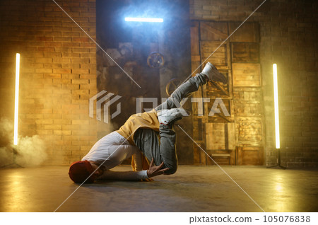 Active stylish guy hip hop dancer training or performing over loft studio 105076838