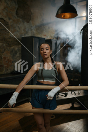 Female fighter with bandaged hands standing leaned at wooden bar Female fighter with bandaged hands standing leaned at wooden bar 105076903