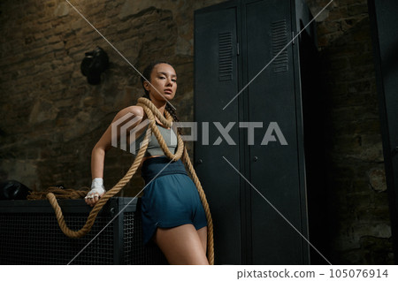 Fashion gorgeous woman boxer wrapped in rope on loft gym background 105076914