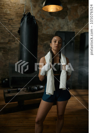 Satisfied woman boxer with towel on shoulders looking at camera 105076924