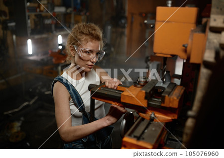 Woman wearing safety protective goggles working on milling and drilling machine 105076960