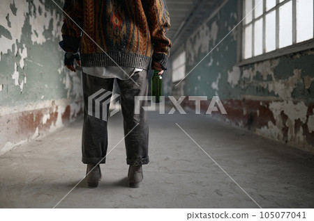 Back view of homeless woman beggar with bottle of alcohol drink in hand Back view of homeless woman beggar with bottle of alcohol drink in hand 105077041
