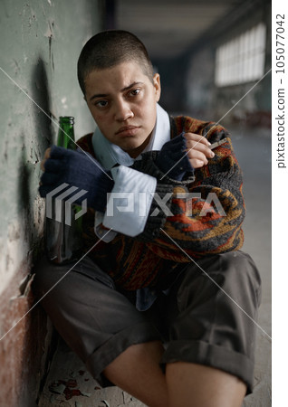 Stressed young woman beggar feeling scared sitting on floor Stressed young woman beggar feeling scared sitting on floor 105077042