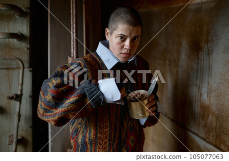 Portrait of hungry homeless castoff young woman eating canned food Portrait of hungry homeless castoff young woman eating canned food 105077063