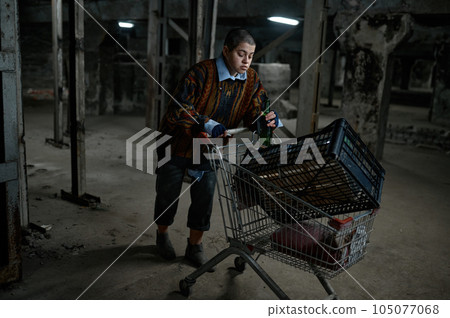 Drunk young homeless woman pushing shopping trolley cart Drunk young homeless woman pushing shopping trolley cart 105077068