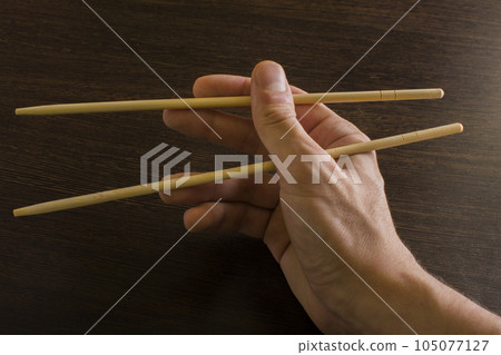 chopsticks in the right hand on the background of wood 105077127