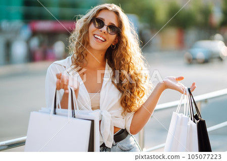 Woman carrying some shopping bags walking on city street. Black friday. Purchases, lifestyle concept 105077223