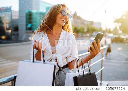 Beautiful woman with shopping bags makes selfie. Woman walking after shopping. Black friday. 105077224
