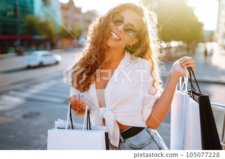 Woman carrying some shopping bags walking on city street. Black friday. Purchases, lifestyle concept Woman carrying some shopping bags walking on city street. Black friday. Purchases, lifestyle concept 105077228
