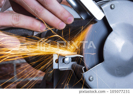 Knife sharpener and hand with blade on wooden table, closeup Knife sharpener and hand with blade on wooden table, closeup 105077231