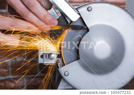 Knife sharpener and hand with blade on wooden table, closeup 105077232
