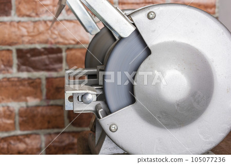 Knife sharpener and hand with blade on wooden table, closeup Knife sharpener and hand with blade on wooden table, closeup 105077236