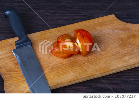 tomato partly sliced with knife and cutting board tomato partly sliced with knife and cutting board 105077237