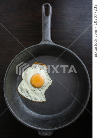 pan with fried eggs on a wooden background 105077238